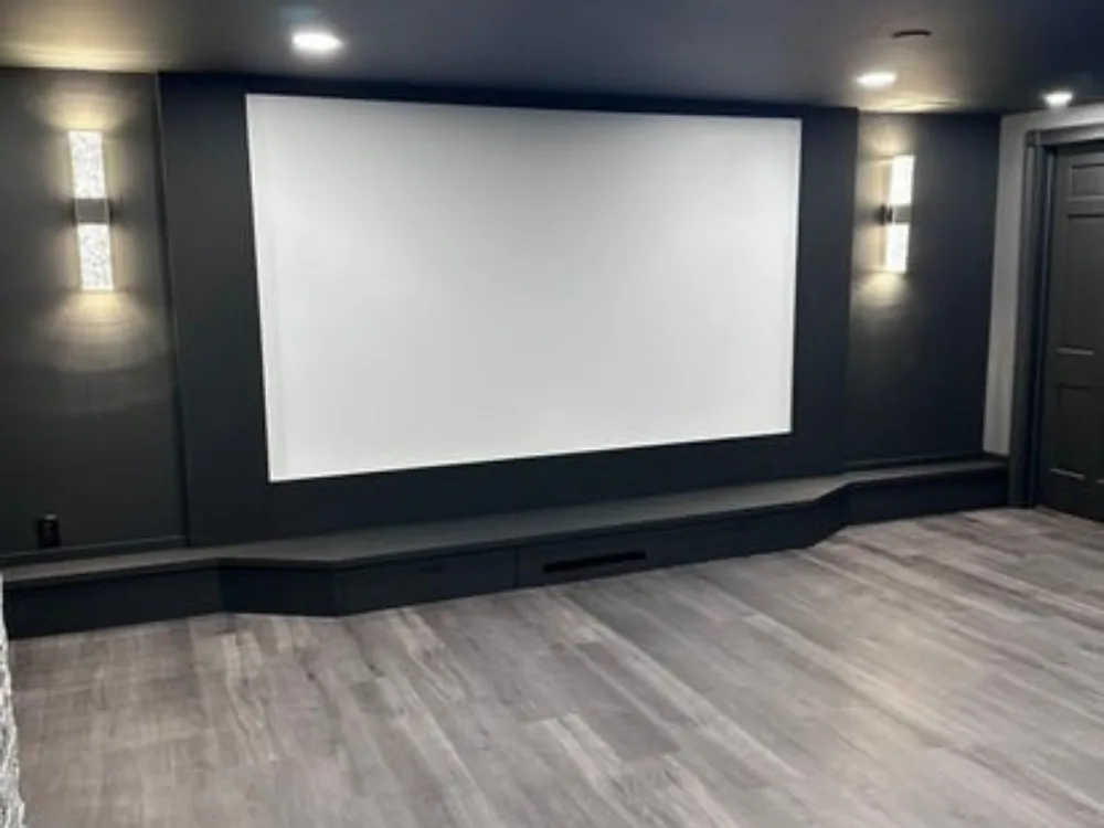 Basement home theater renovation featuring projector screen and modern lighting.