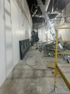 Commercial interior renovation in progress with workers and scattered debris.
