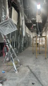 Commercial interior renovation with worker installing lighting on scaffolding.