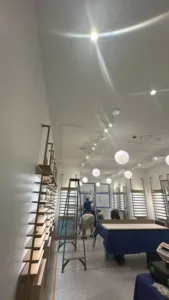 Commercial interior renovation with shelving installation and ceiling lighting.