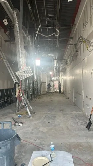 Commercial interior renovation hallway under construction with ducts and cables.